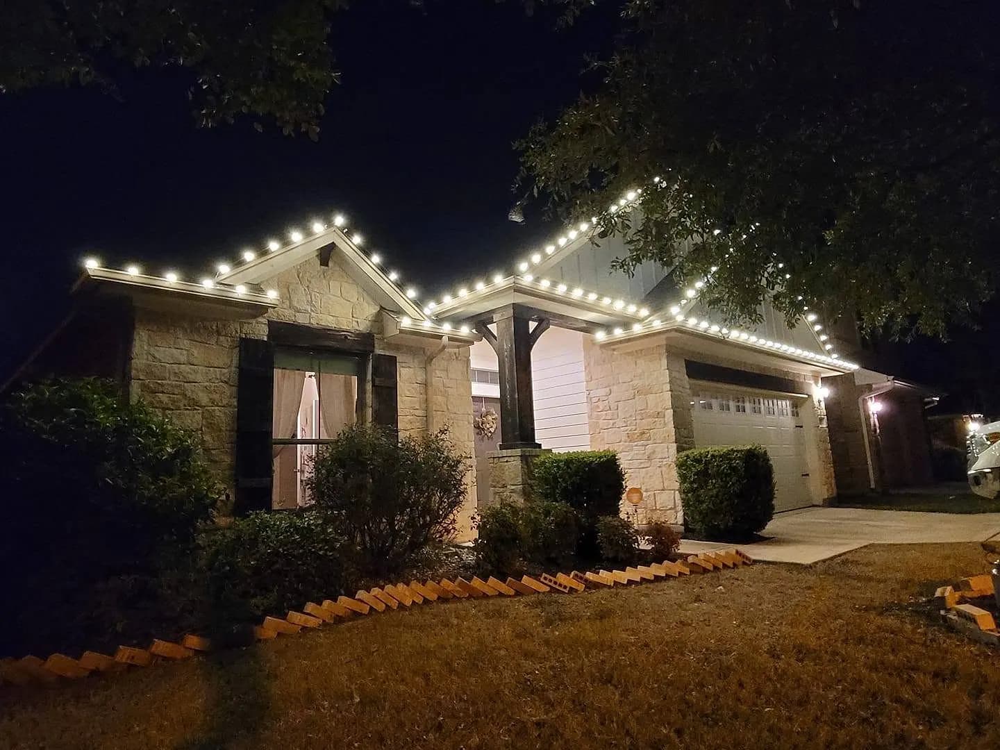 Stone home with warm white C9 lights tracing every roofline peak
