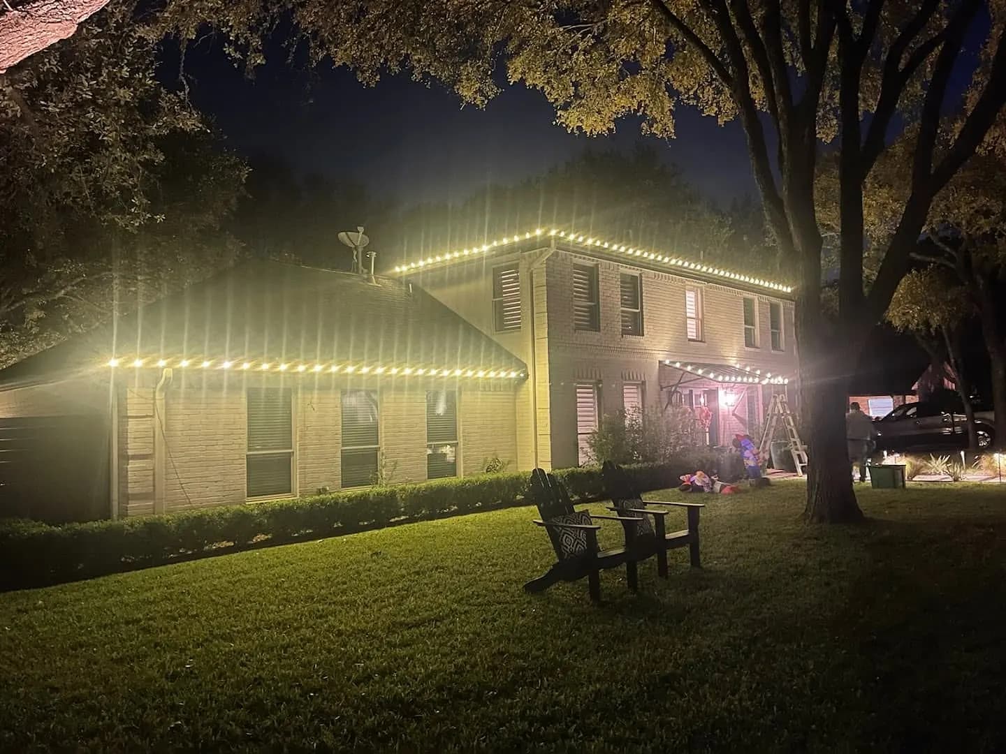 Two-story home with warm white lights along the eaves and peaks